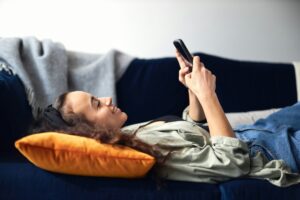 Eine Frau liegt auf dem Sofa und scrollt durch TikTok