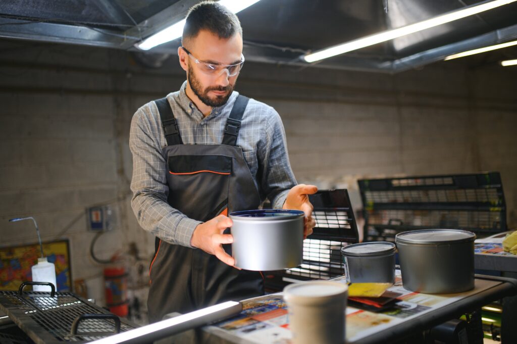 printing house, experimented technician works on UV printer. Production work.